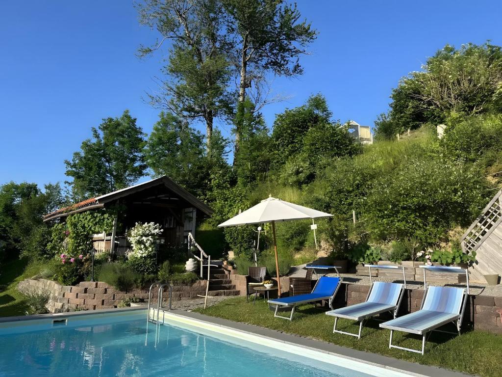 a swimming pool with chairs and an umbrella next to it at Ferienwohnung Elfi in Oberreute