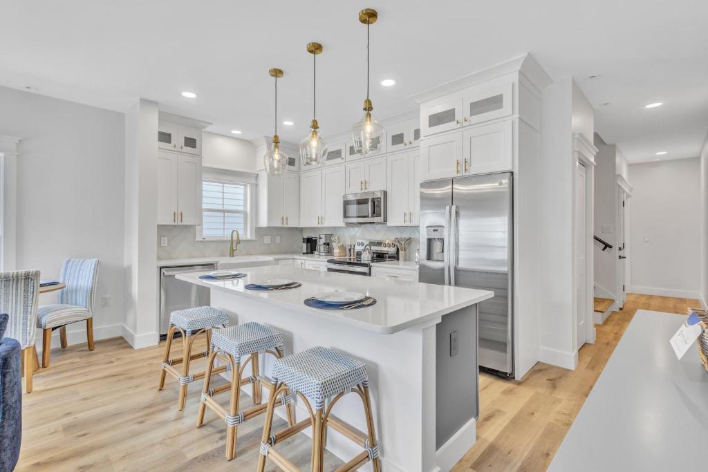 a kitchen with white cabinets and a large island with bar stools at 200 Olive Shell Court in Hilton Head Island