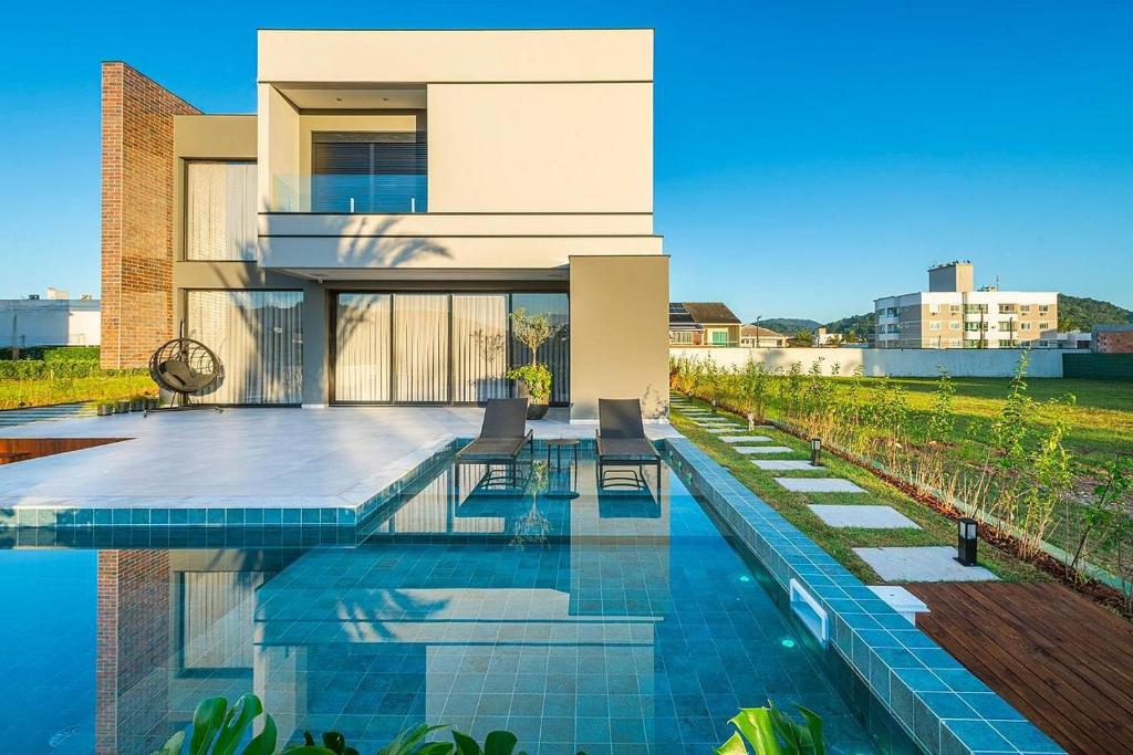a house with a swimming pool in front of it at Casa Golf in Camboriú