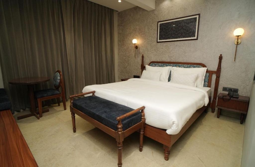 a bedroom with a large bed with a bench in it at Hotel Manjushree in Pachmarhī