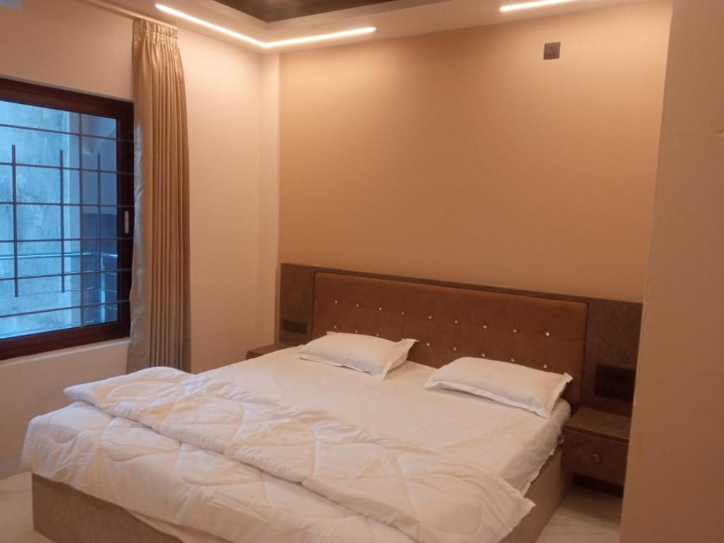 a bedroom with a bed with white sheets and a window at SringeriRooms in Sringeri