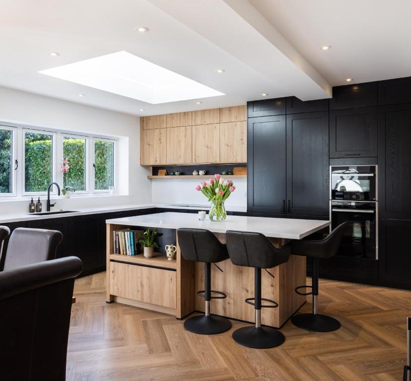 a kitchen with black cabinets and a island with black bar stools at Swissalpschalet Timber Inn 1st floor, 6 persons in Blatten bei Naters
