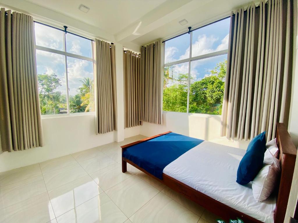 um quarto com uma cama com lençóis azuis e janelas em Galle Breezy Nest em Nikawatawana