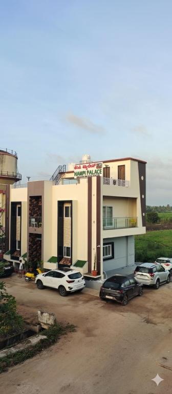 a building with cars parked in a parking lot at Hampi Palace in Hampi