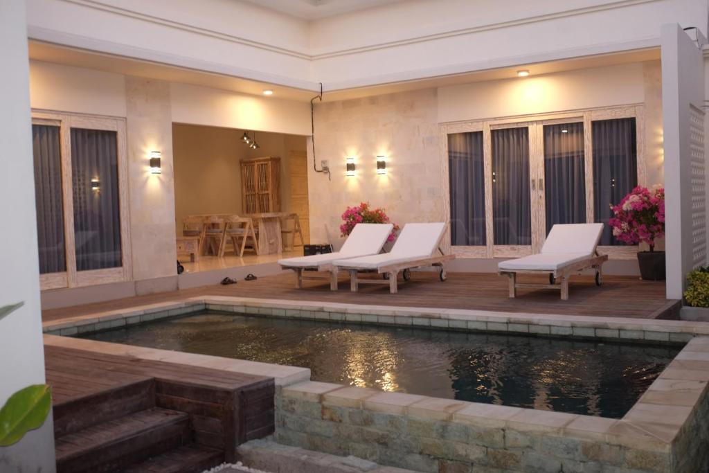 a swimming pool in a house with two chairs and a table at the gosana in Amed