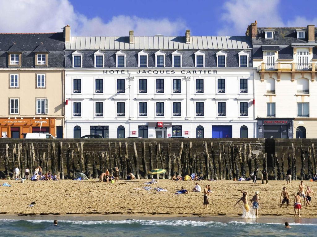 a group of people on the beach in front of a building at ibis Saint Malo Plage in Saint Malo