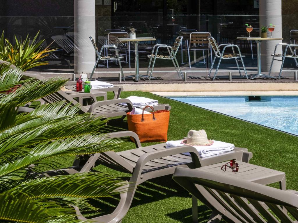 a group of chairs and tables next to a pool at ibis Hyeres Centre in Hyères