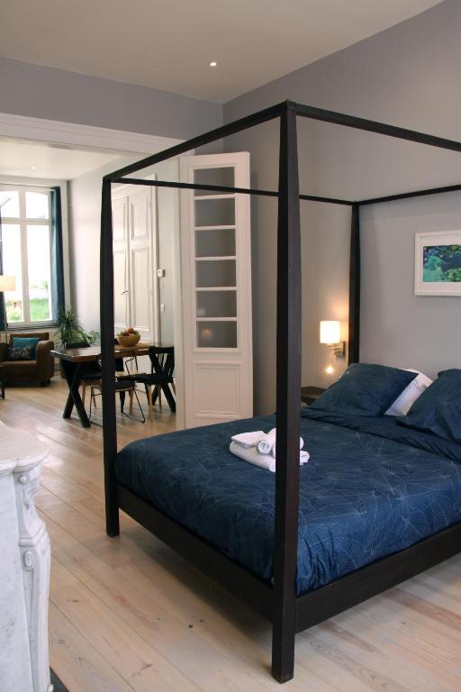 a bedroom with a four poster bed with blue sheets at Le Jardin de Ligny in Saint-Omer