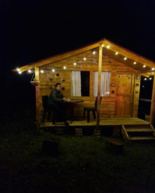 a man sitting at a table in front of a cabin at Cabaña alto de torres in Guatavita