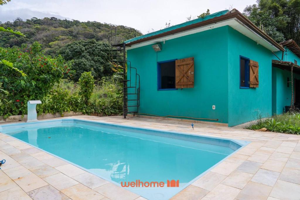 a villa with a swimming pool in front of a house at Kitnet em Aldeia Velha com piscina e churrasqueira in Silva Jardim