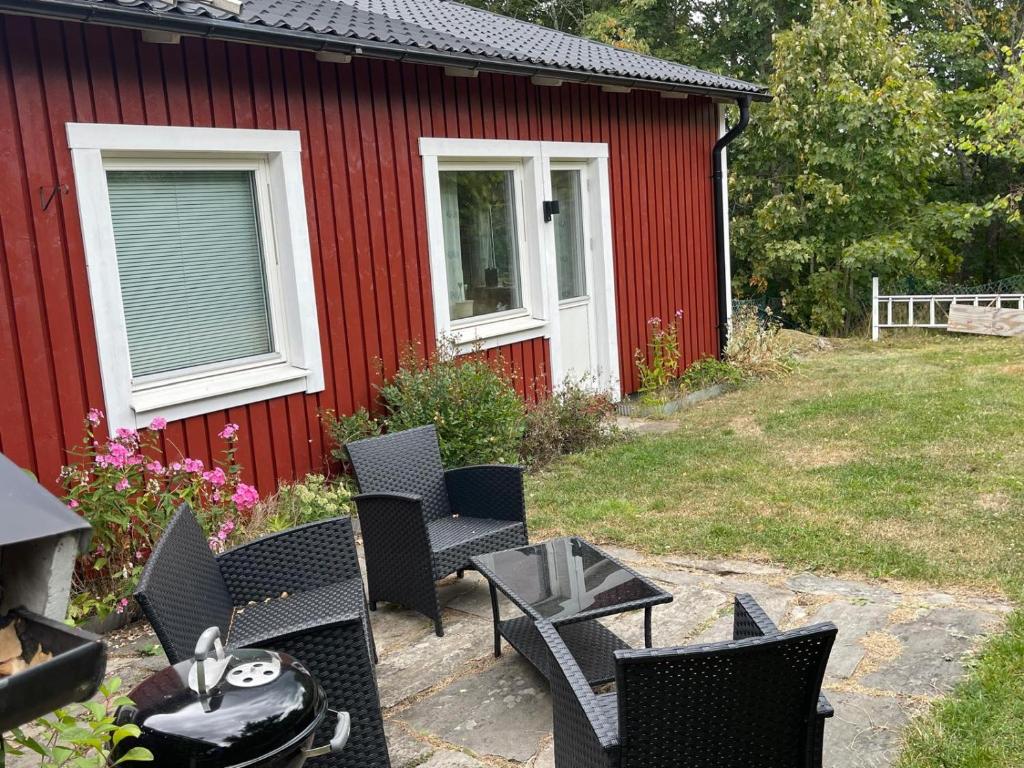 a patio with chairs and a table next to a red building at Ådalsvägenhus in Fågelfors