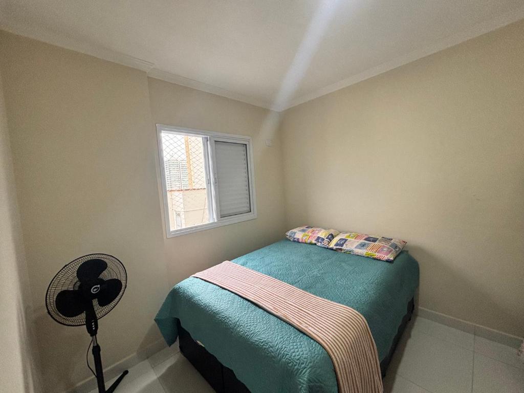 Apartamento Praia Grande caiçara في برايا جراندي: غرفة نوم صغيرة بها سرير ونافذة