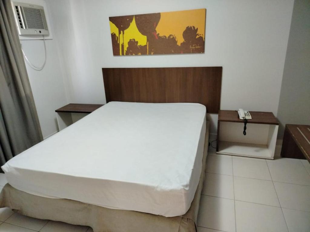 a bedroom with a large white bed and a nightstand at Boulevard Suite in Caldas Novas