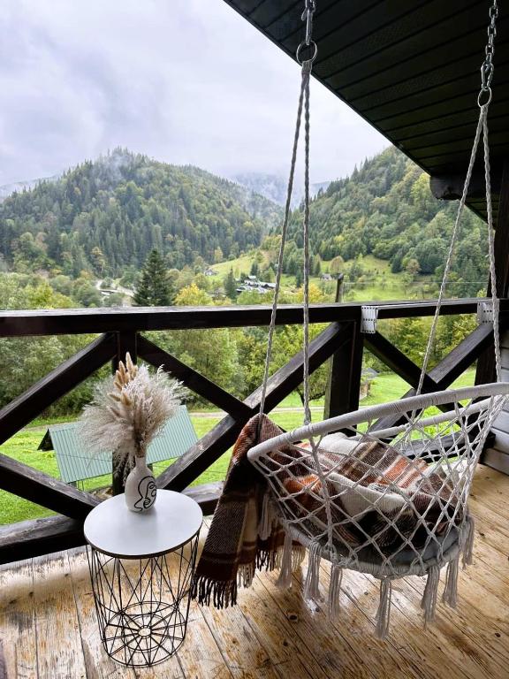 a swinging chair on a porch with a view at Котедж Ксенія in Dzembronya