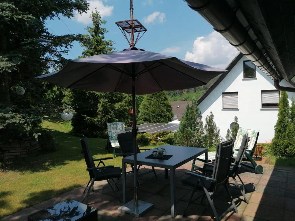 une table et des chaises avec un parasol sur une terrasse dans l'établissement Häuschen in grüner Idylle, à Berggiesshübel