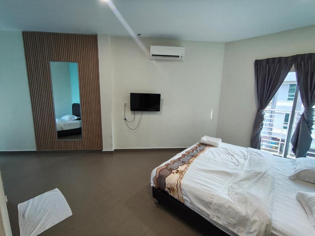a bedroom with a bed and a television and a mirror at Mass Hotel in Kampong Kerayong