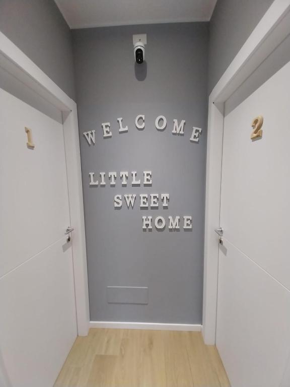 a hallway with two doors and a welcome sign on the wall at Litte Sweet Home - Abbiategrasso città in Abbiategrasso