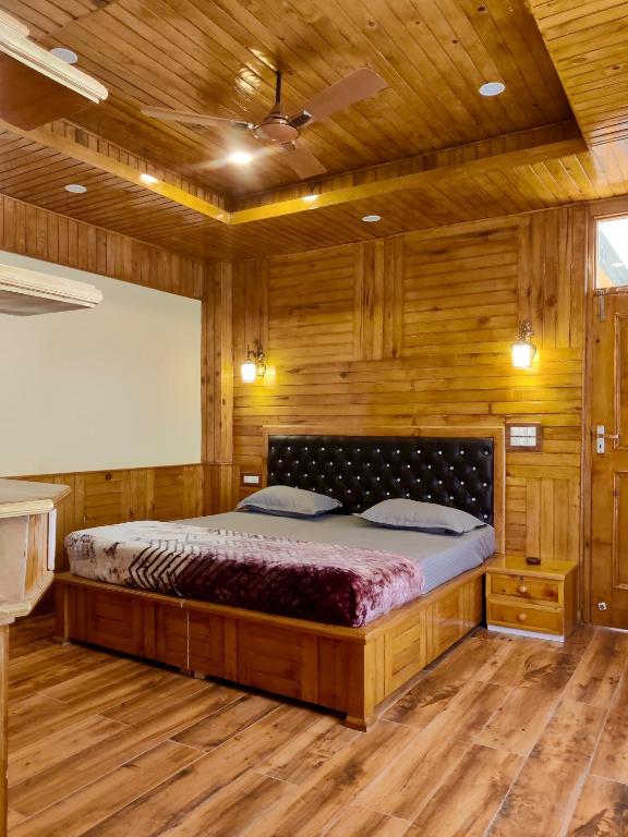 a bedroom with a large bed in a room with wooden walls at Khaapus Home Naggar in Nagar