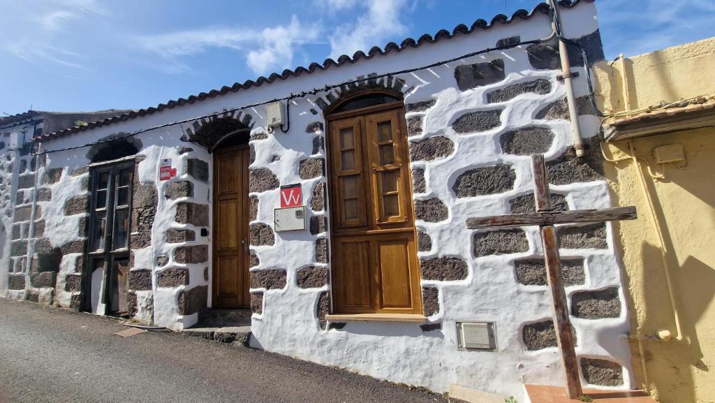 Un edificio de piedra con puertas de madera en una calle. en Cozy Canarian House La Casa de mis Abuelitos by HRTenerife Net, en Los Silos