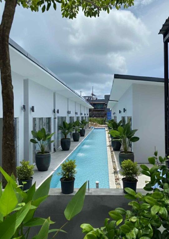 a swimming pool next to a building with potted plants at A&J Holiday Villa in Ban Na Bon