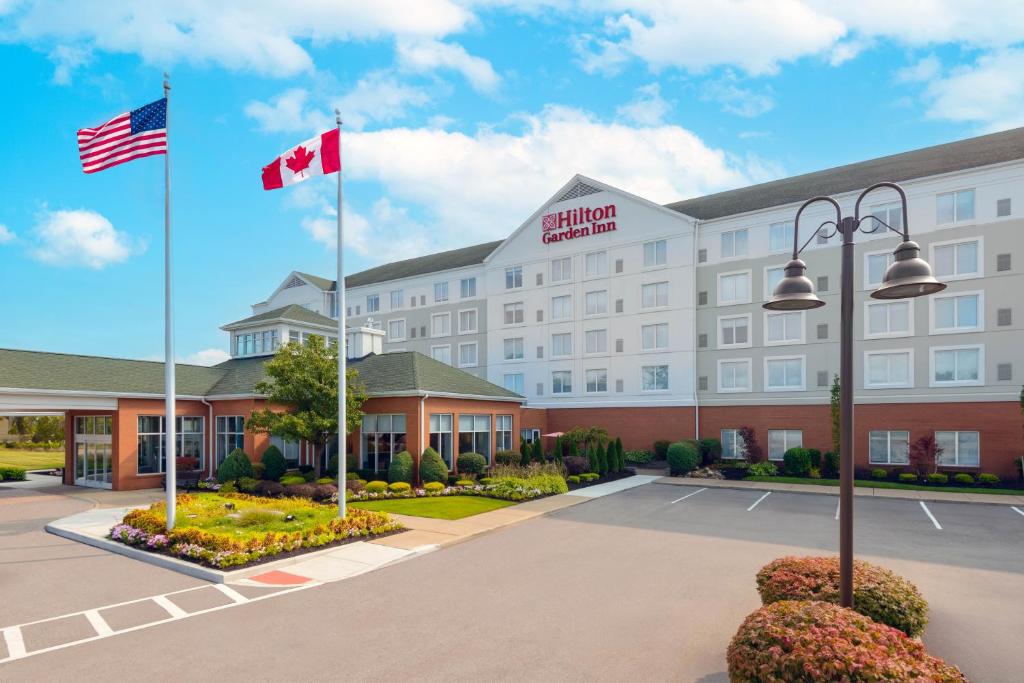 a hotel with two canadian flags in a parking lot at Hilton Garden Inn Buffalo Airport in Cheektowaga