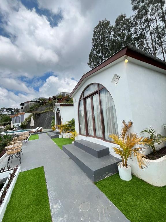 a white house with a patio and grass at jungle camping in Baturaja