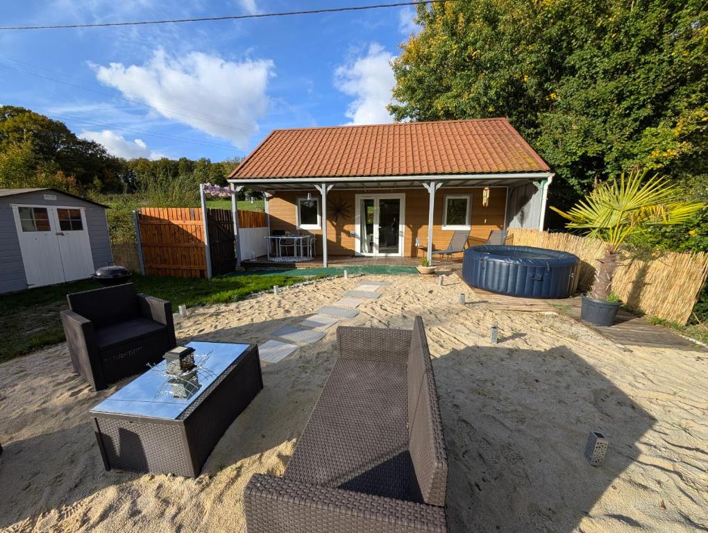 a backyard with a house and a table in the sand at Gîte du Jarrier in Bonnefoi