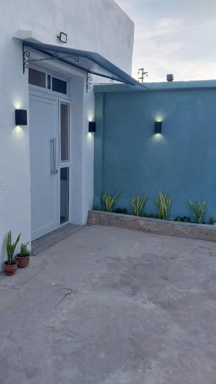 a blue and white building with a door and plants at Depto Edu in Rafaela