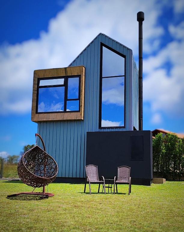 a small house with two chairs and two windows at Tiny House Cambará in Cambara do Sul