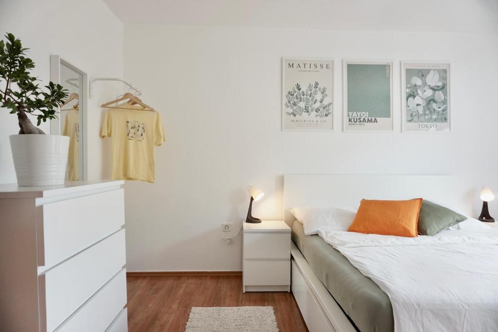a white bedroom with a bed and a dresser at NEU Gemütliche Wohnung für max 5 Personen mit Balkon nähe Mosel mit Blick auf die Weinberge in Koblenz