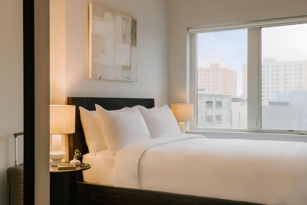 Un dormitorio con una gran cama blanca y una ventana. en Sosuite at The Ovation - Ave of The Arts, en Filadelfia