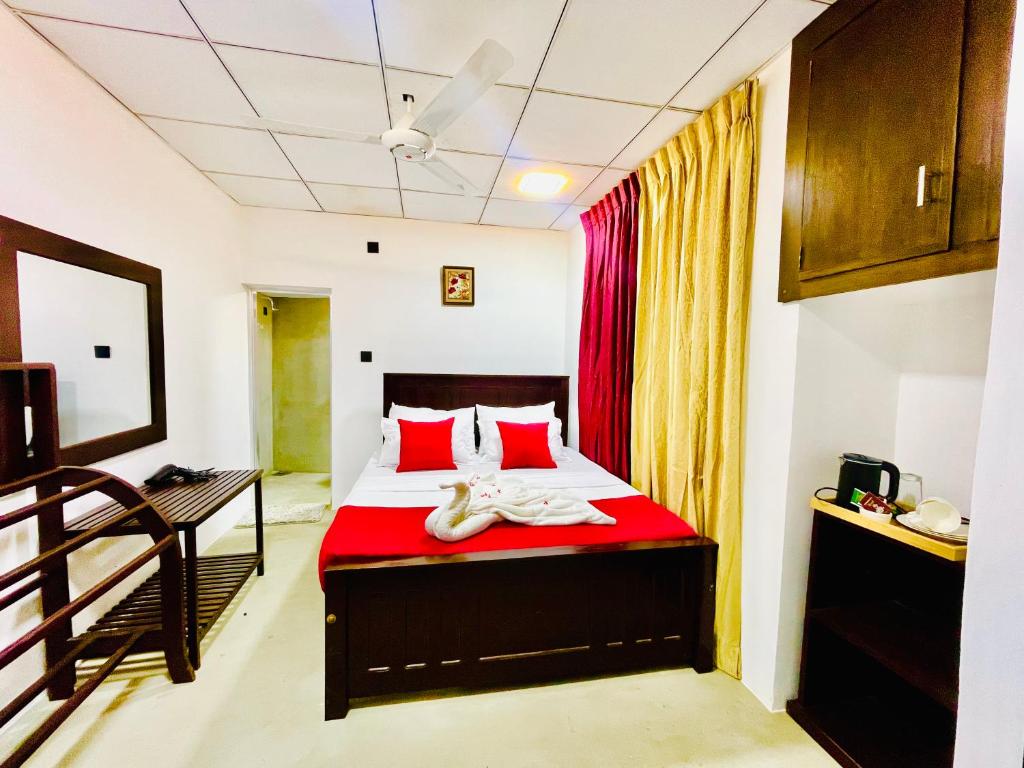 a bedroom with a bed with red pillows at The Lavish Polonnaruwa in Polonnaruwa