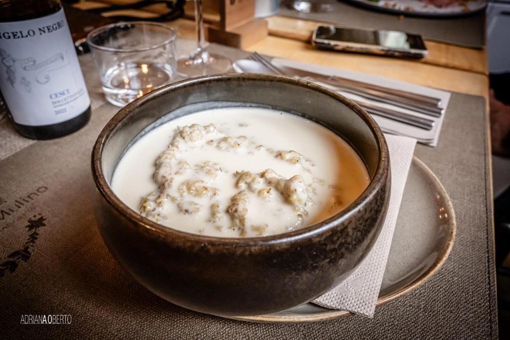 a bowl of soup on a table with a bottle of wine at B&B Locanda Del Mulino in Pamparato