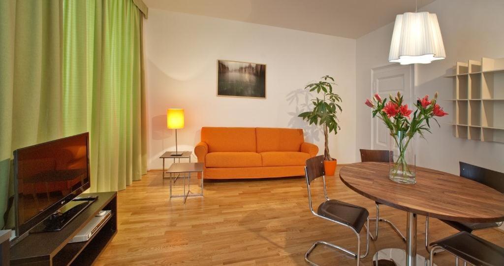 a living room with an orange couch and a table at Schlossquadrat Apartment 17 in Vienna