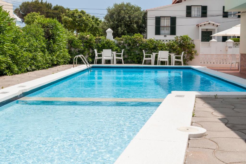 una piscina en un patio con sillas y una casa en Hotel Madrid en Ciutadella