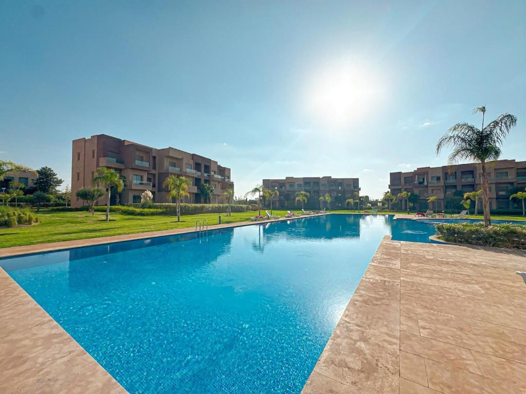 a large blue swimming pool with buildings in the background at Cocon Prestigia Argan avec piscine & parking in Marrakech