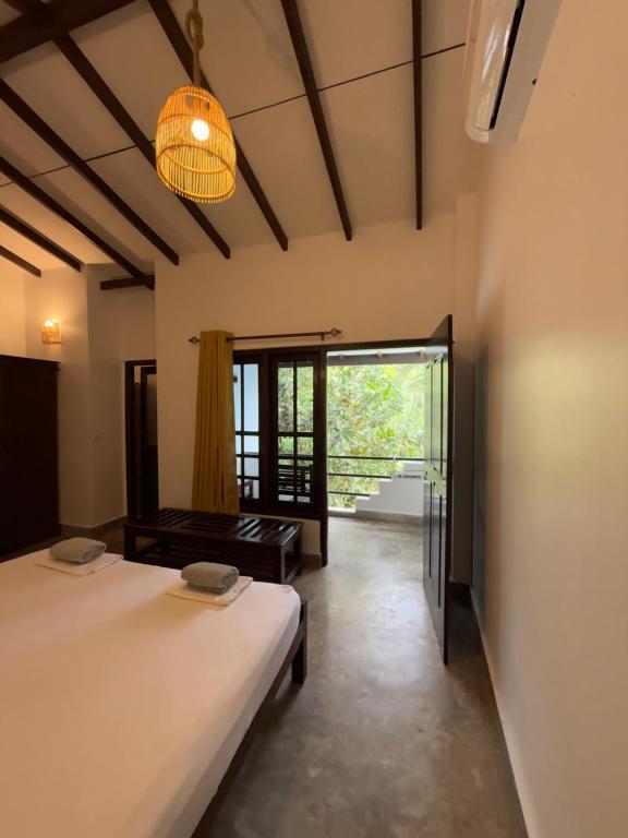 a room with two beds and a large window at Riverside Cabanas in Mirissa