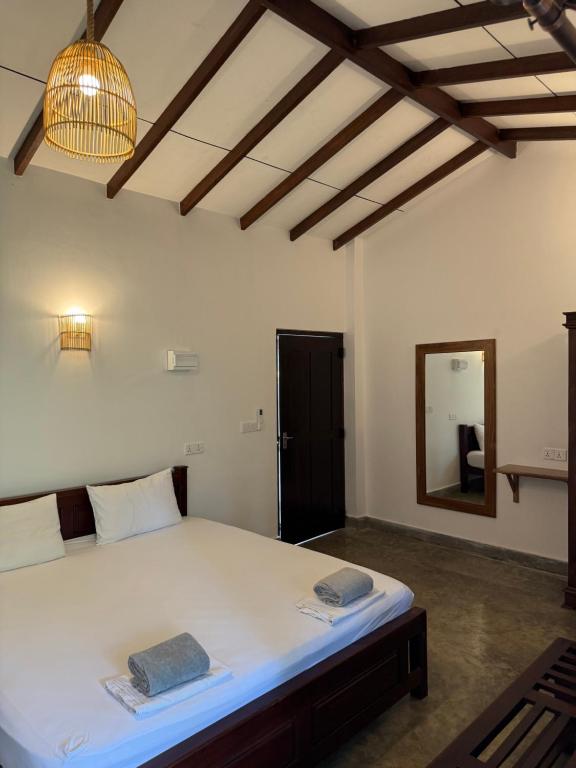 a bedroom with a large white bed and a mirror at Riverside Cabanas in Mirissa
