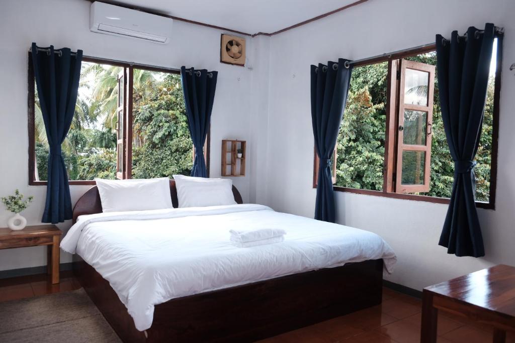 a bedroom with a large bed and two windows at Sabaydee Guesthouse in Ban Houayxay