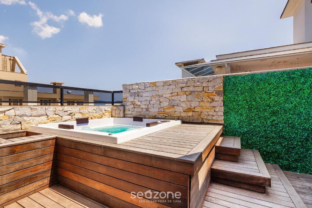 a hot tub on a deck with a green wall at House with Jacuzzi, just 10min from the sea OSH in Florianópolis