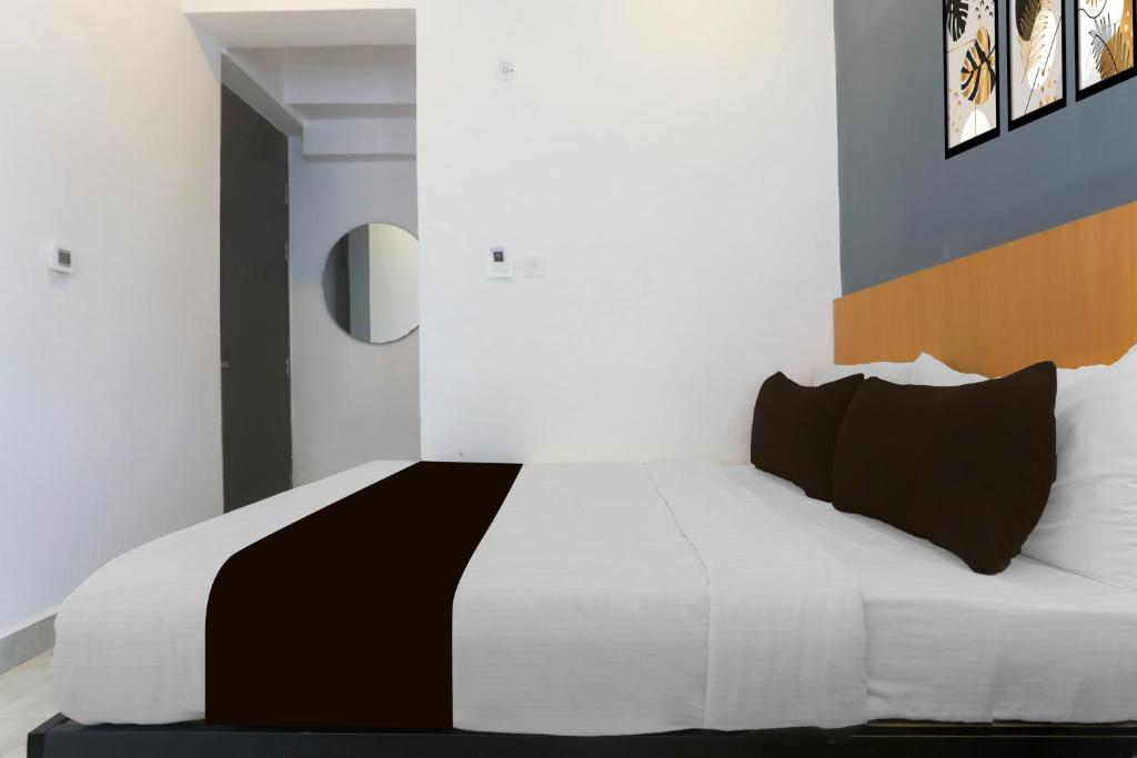 um quarto com uma cama branca e almofadas pretas em Hotel O Vivek inn Palace em Prayagraj