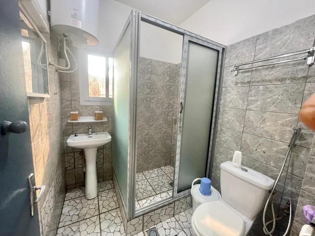 a bathroom with a shower and a toilet and a sink at Maison Meublé de 3 CH Essos in Yaoundé