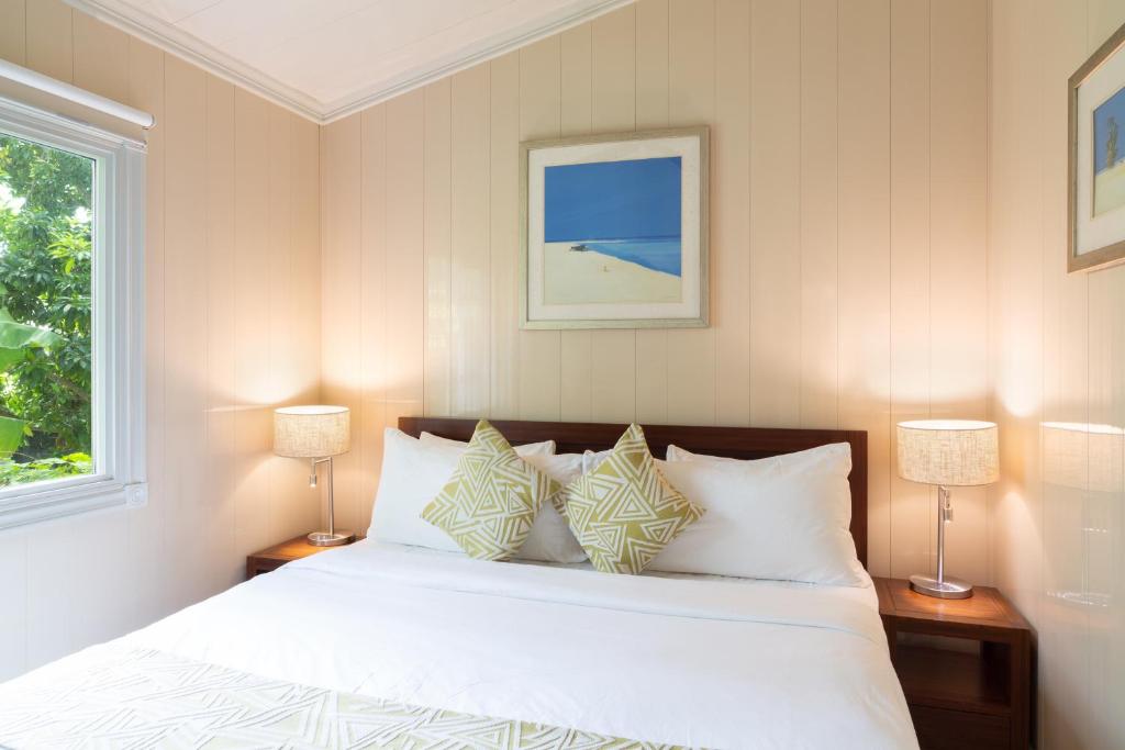 a bedroom with a bed with two lamps and a window at Kokomo Deluxe King - King Cottage in Turtle Cove
