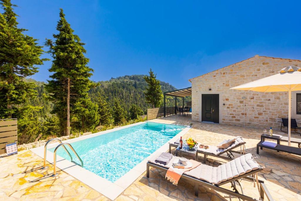 a pool with chairs and an umbrella next to a building at Villa Hill View Ena in Chourdátika