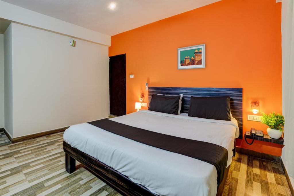 a bedroom with a large bed with an orange wall at Hotel O PMR Hotel in Bengaluru