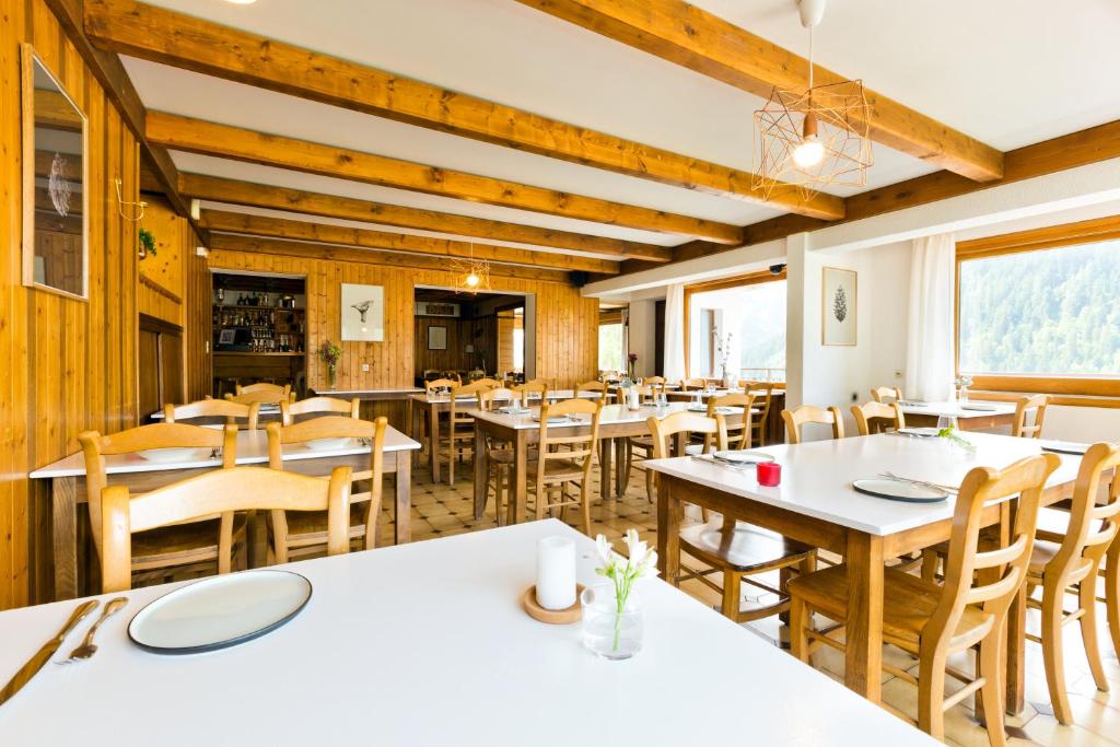 een eetkamer met witte tafels en stoelen bij Le Roitelet in Châtel