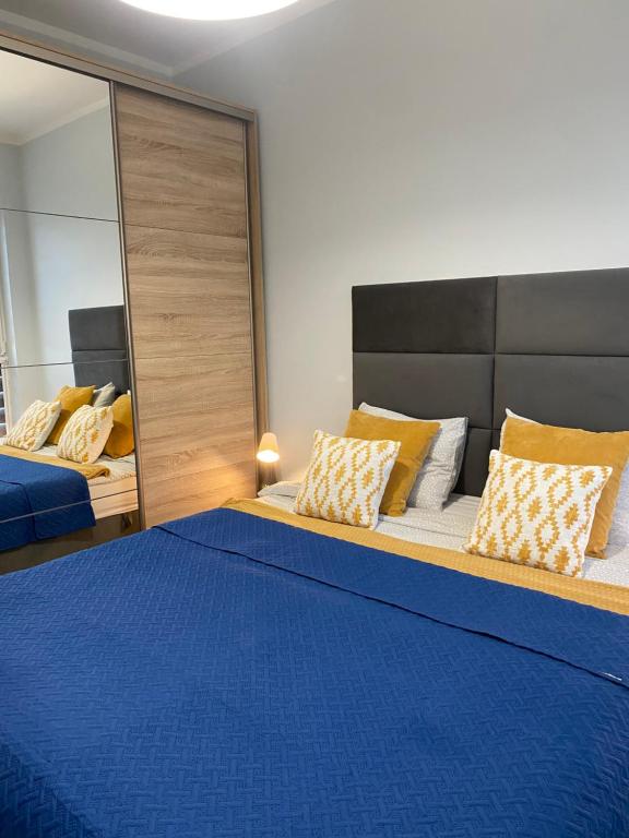 een slaapkamer met een blauw bed en een spiegel bij Good Time Apartments 104 Komfortowy apartament w sercu Starego Miasta in Poznań