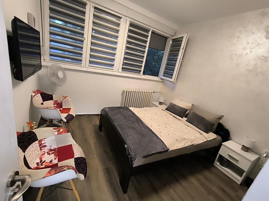 a bedroom with a bed and a chair and windows at Nina Urban Apartment-Novi Beograd in Belgrade