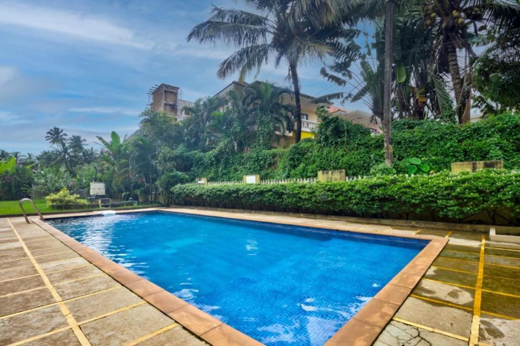 a swimming pool with blue water and palm trees at Marvella 3BHK Luxury Villa with Shared Pool in Arpora