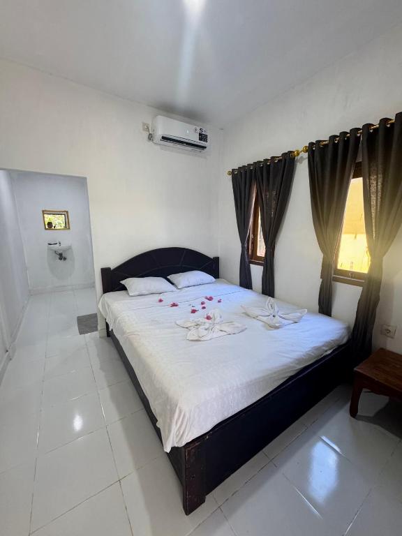 a bedroom with a large bed with red flowers on it at Gina's Reading Homestay in Pulau Lebur